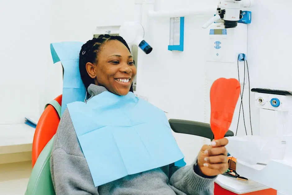 Smiling woman holding a mirror during a dental check-up in a clinic.