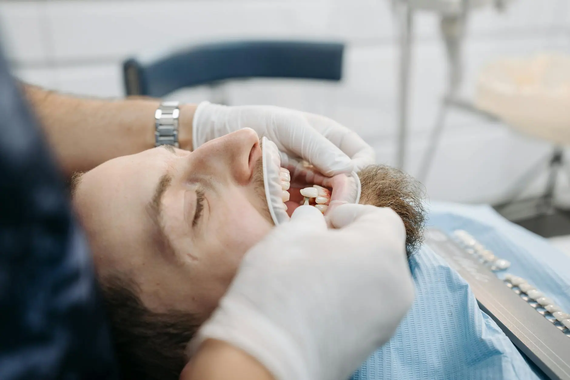 Dentist using shade guide to match patient's teeth color in dental clinic.