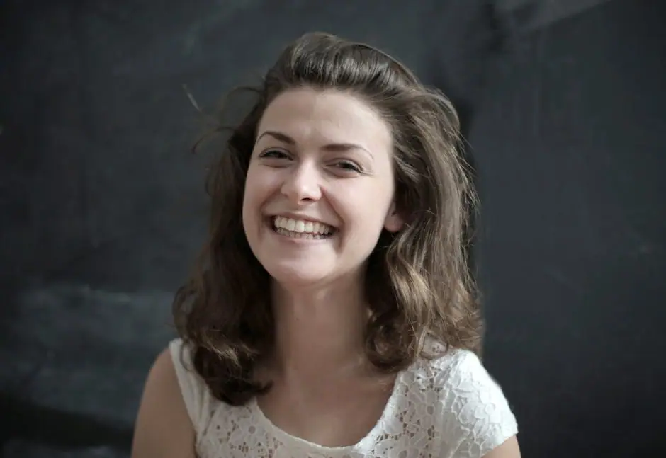 Portrait of a cheerful woman with a radiant smile against a dark backdrop.
