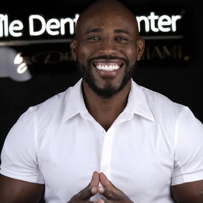 Smiling patient in front of the Smile Dental Center Miami sign